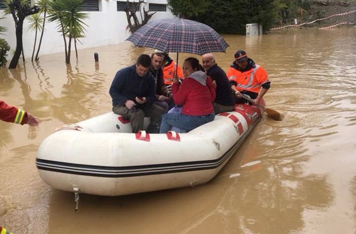 Protección Civil Marbella ayuda con una lancha a varias personas por la lluvia